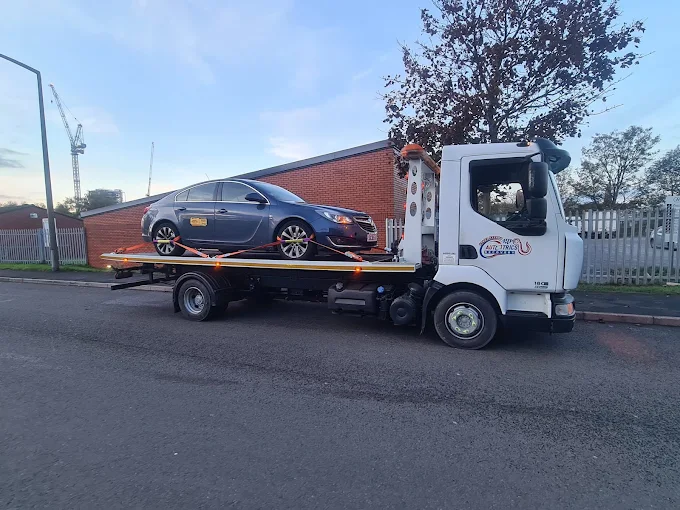 Car recovery truck transporting a taxi vehicle on a roadside in Wolverhampton, West Midlands