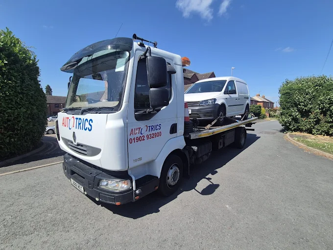 Car recovery truck transporting a white van on a residential street in Wolverhampton, West Midlands
